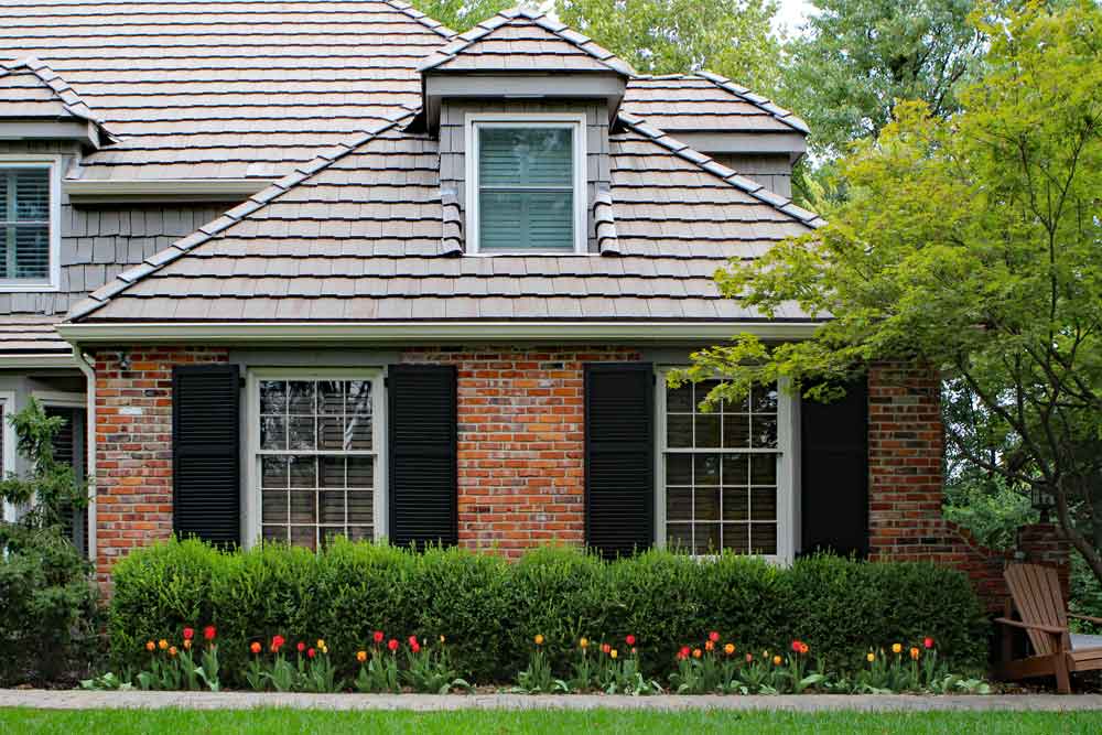 Black wood shutters installed on a brick house.